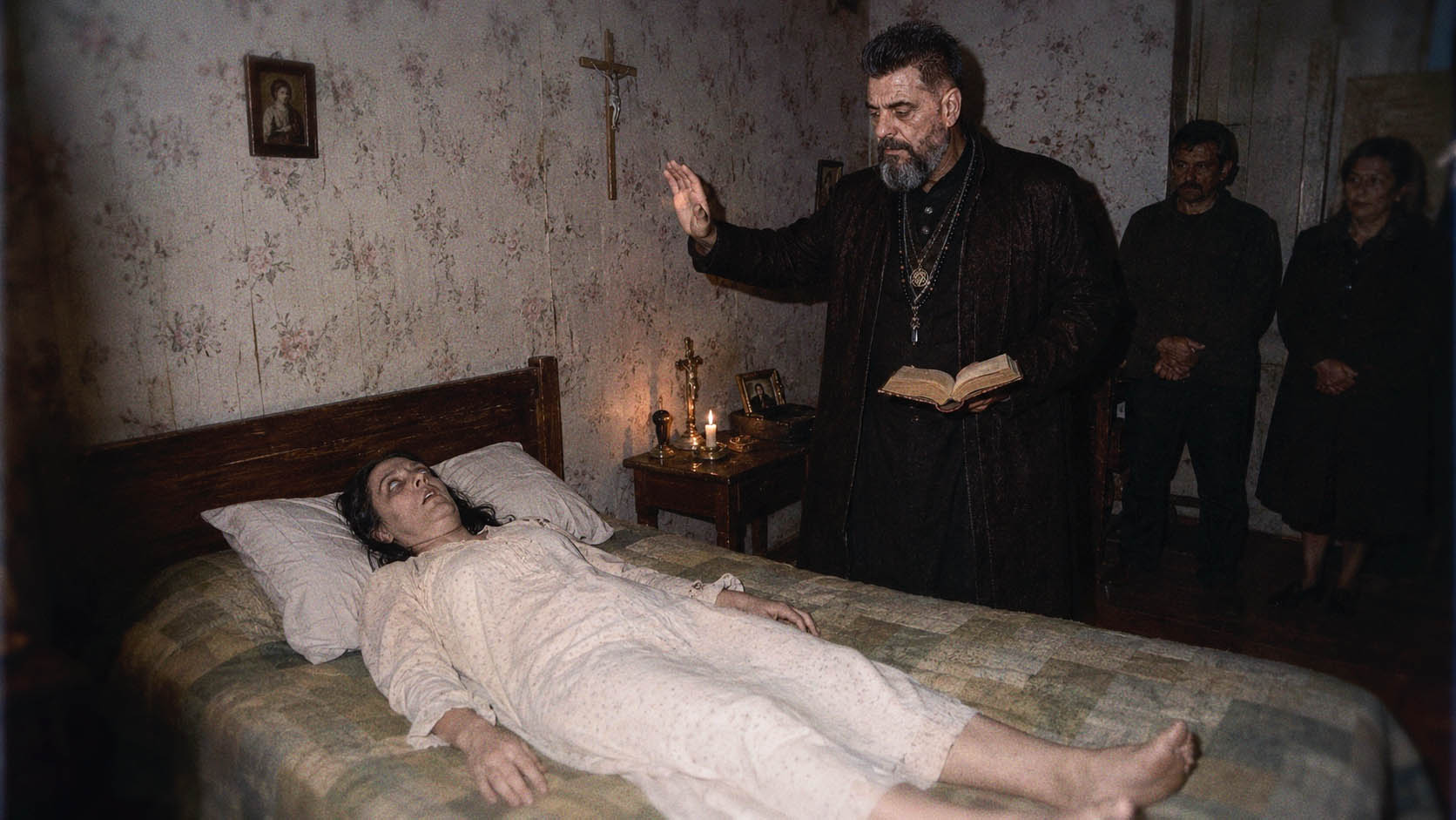 Victor Draconic performing an exorcism ritual beside a woman in a candlelit room while assistants observe